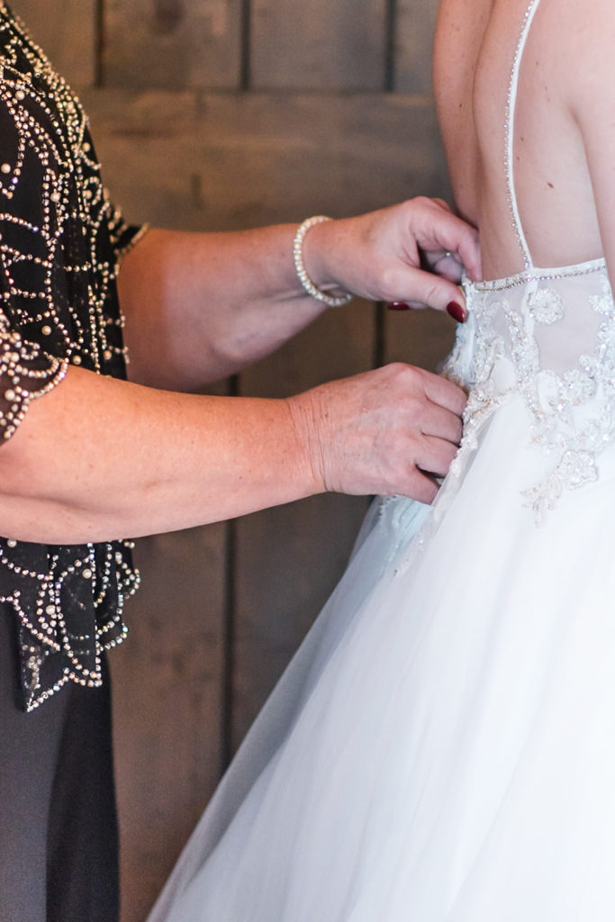 The mother of the bride zips the bride's wedding dress at her elopement
