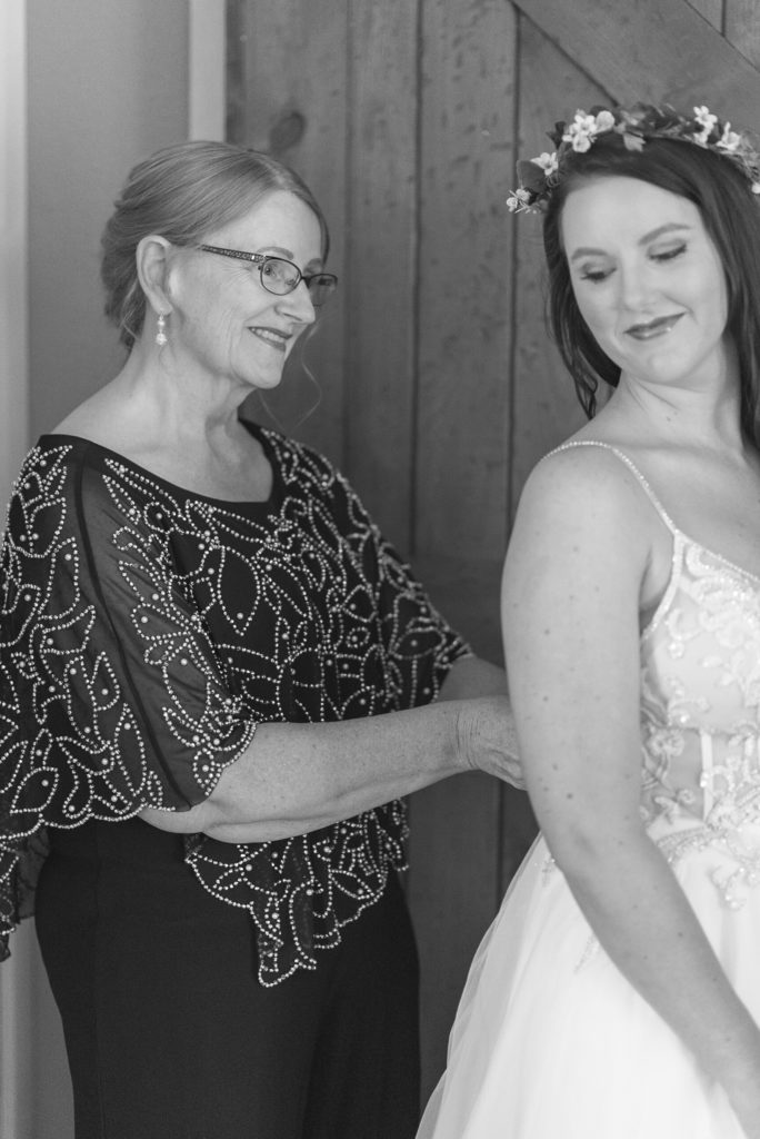 The mother of the bride zips the bride's wedding dress at her elopement