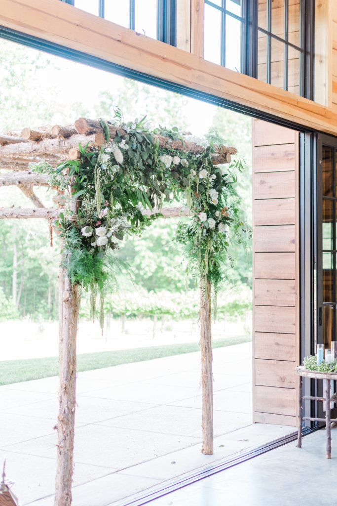 Charlotte floral designer Proper Flower installs a beautiful white with greenery arbor for the wedding ceremony
