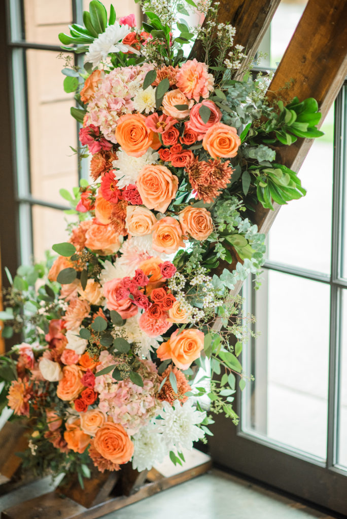 Charlotte Floral Designers with another beautiful wedding ceremony arbor with coral, peach, white, and greenery
