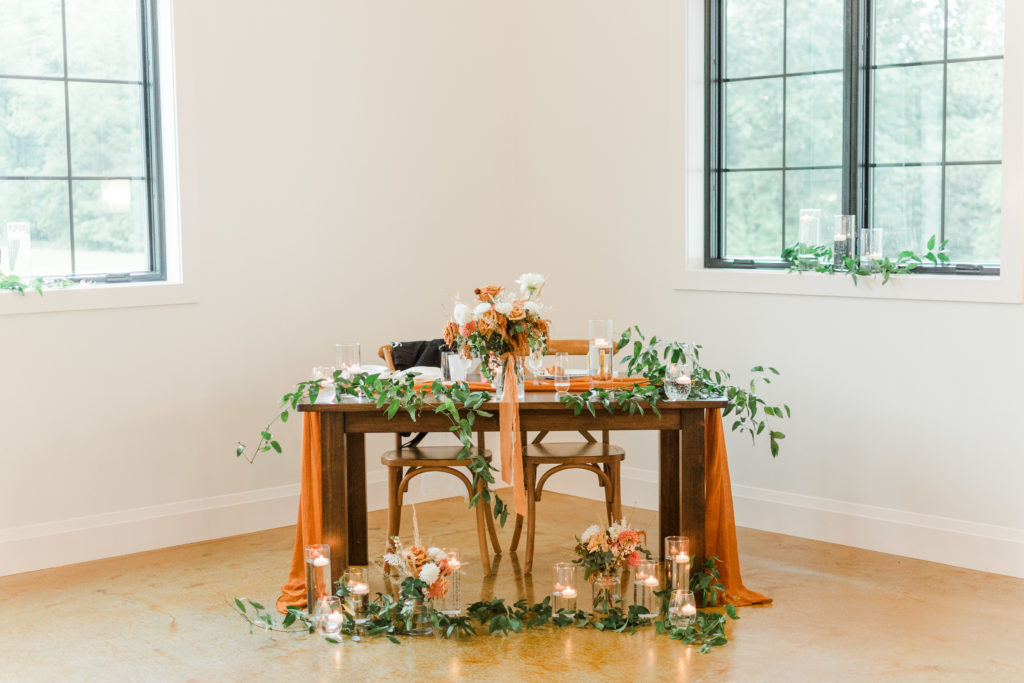 Terra Cotta, eucalyptus, and navy sweetheart table at a wedding reception after an autumn wedding at Hazelwood Weddings