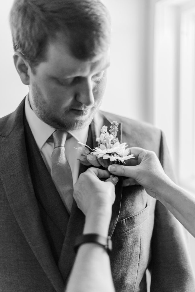 Groom pinning his boutonniere before his Circle M Farm wedding 